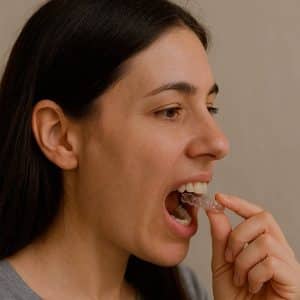 Mujer joven colocando alineador invisible en sus dientes, tratamiento de ortodoncia Invisalign
